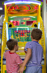 Entertainment center and children's area with slot machines. Two boys throws basketball in basket. Basketball arcade game.
