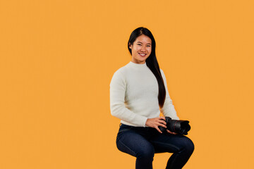 Portrait of a professional Asian female photographer, holding a camera.