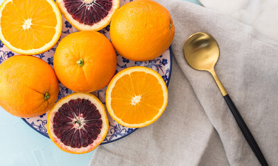  Close up whole and half naval and blood oranges with a golden spoon.