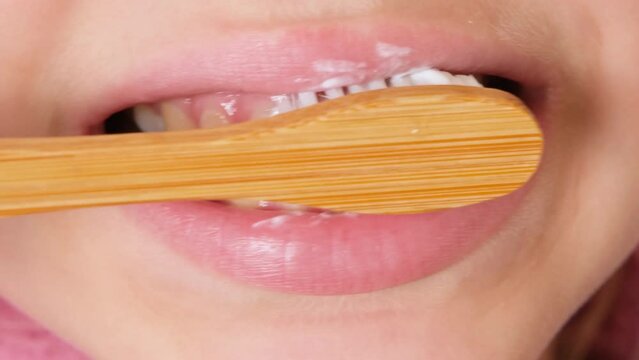 Child girl or teenage girl of eleven years old brush her teeth with eco toothbrush made of natural materials. Concept of dental hygiene, dental care and health.