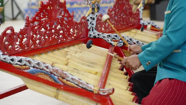 Asian man's playing traditional bali music in temple. Close up of male musicians in national balinese clothing, dress use bamboo instrument xylophone Rindik on ceremony 