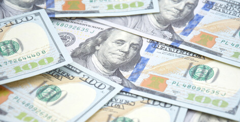 A pile of one hundred US banknotes with president portraits.