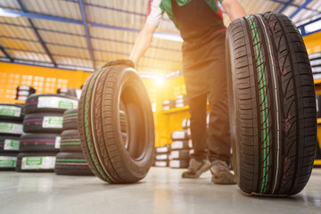 A male tire changer is in the process of checking new tires in stock to take them to a service center or auto repair shop. Tire warehouse for the automobile industry