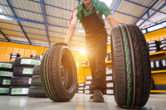 A male tire changer is in the process of checking new tires in stock to take them to a service center or auto repair shop. Tire warehouse for the automobile industry