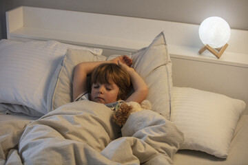 Little boy sleeping in bed. At night, the toddler sleeps in his room. Lifestyle.
A child's healthy...