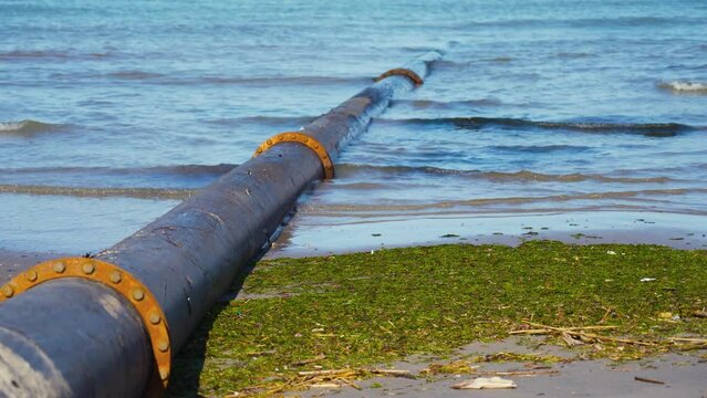 A large tube goes under the sea water at the beach