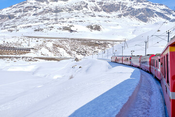 Obraz premium Bernina mountain pass. The famous red train is crossing the white lake. Amazing landscape of the Switzerland land. Famous destination and tourists attraction
