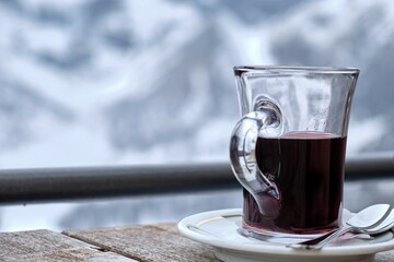 Winter holidays in a ski resort, mountain vacation, glass of red hot wine against the backdrop of snow-capped mountains, in Swiss alps
