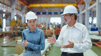 Two professional engineer man and woman manager leader wearing helmet walking in factory talking and discussing for work - Powered by Adobe