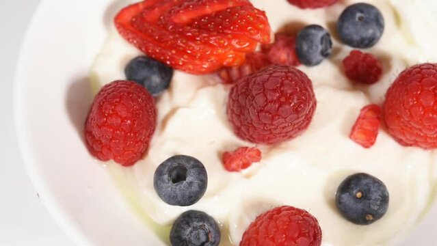 uno yogurt grecco con frutti rossi sopra, yogurt con lamponi fragole e mirtilli

