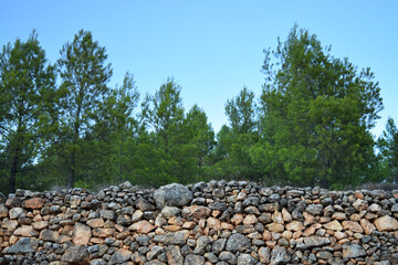 View of an old stone wall of stacked rocks in a forest or country place. Agricultural terrace