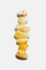 Aesthetic minimal pattern, set of amber stones gradient color on white background. Line composition from natural gemstones. Summer concept of harmony, spa. Top view, flat lay. Still life