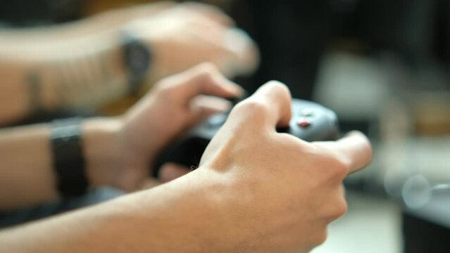 Two young students are playing a video game using a controller. Close up of hands and joypad