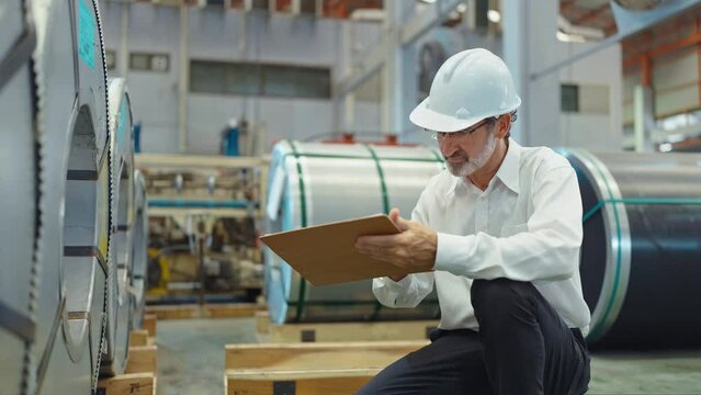 Engineer manager leader man wearing helmet sitting at manufacturing factory recheck the detail of product on paper board in workplace area