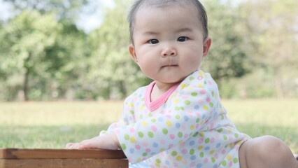 Cute asian baby girl sitting on a picnic mat and looking at camera.
