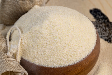 Semolina is poured on the table and in a wooden bowl