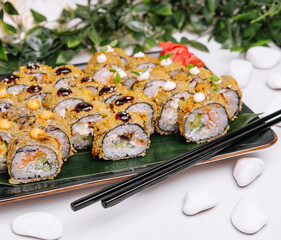 Served warm sushi with ginger and wasabi on a black stone plate.