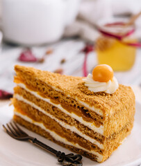 Layered orange cheesecake on plate on wooden table