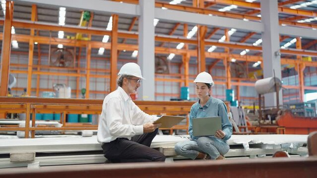 Two engineer manager leader and woman assistant holding laptop and shaking hands for making together after processes order at metal factory