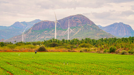 Windmill - Wind turbine below the mountain on the agriculture land. Alternate energy source generator with environment friendly. Wind turbines for ecological power supply ..