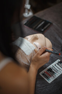 Beauty master lashmaker makes a young girl client eyelashes with tools