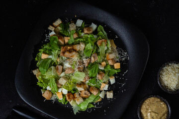 Caesar salad on a black plate close-up