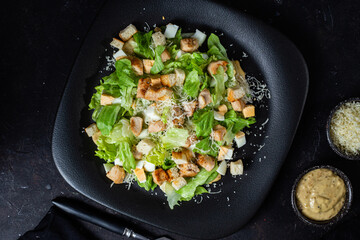 Caesar salad on a black plate close-up