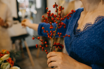 Woman holding a branch with red ilex winter berries. 