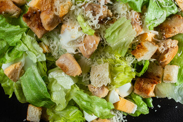 Caesar salad on a black plate close-up