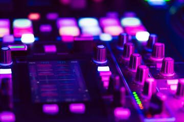 Close up of DJ mixing console in party light