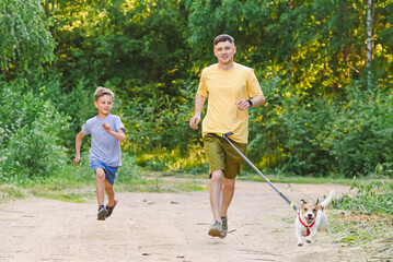 Father and son jogging along country dirt road with dog on waist leash