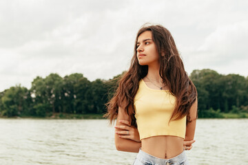 Obraz premium Slim woman walking barefoot along the river sea lake. Female on beach island with splashing waves and foam. Girl tourist on vacation, weekend relaxing resting resort. Lady go on shore, sunbathing