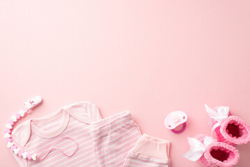 Baby accessories concept. Top view photo of pink infant clothes shirt pants dummy teether chain and knitted booties on isolated pastel pink background with empty space