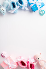 Baby accessories concept. Top view vertical photo of pink and blue knitted booties gift boxes teddy bear toys and pacifiers on isolated white background with copyspace