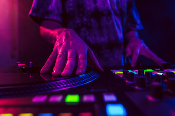 Close up of DJ hands on dj console mixer during concert in the club