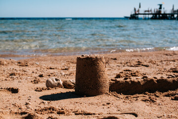 Sand tower on the beach. Children's beach toys - buckets, shovel and shovel on the sand on a sunny day