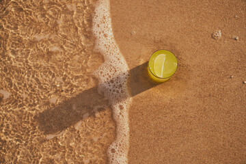 Image of a refreshing lemonade on the sand by the sea. Picture of cocktail among the waves by the sea at the beach. Visual evocative of a summer vacation trip in a tropical location.
