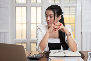 A businesswoman sits at her desk contemplating problems and questions from project work.