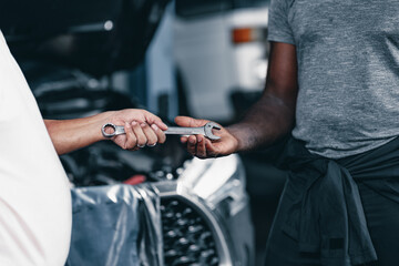 Mechanics Hand send a wrench tool to a friend. Automobile Garage Worker Teamwork Repair Service Concept.