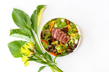 Salad with medium roasted beef and greens on a white background