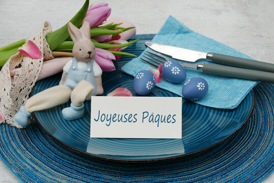 D&eacute;corations de table festives pour P&acirc;ques avec assiettes, couverts, d&eacute;corations de P&acirc;ques et le texte Joyeuses P&acirc;ques sur une carte de place.