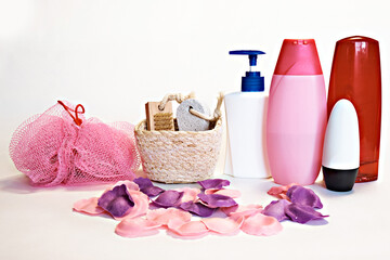 Obraz na płótnie Canvas Pink washcloth, shampoo, liquid soap, aromatic bath leaves, a basket with a brush and pumice stone for feet and other toiletries on a white background. Spa procedures.