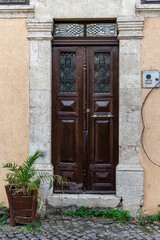 Fototapeta na wymiar Old wooden dark brown double glass door in a stone wall with iron railings in Antakya, Hatay, Turkey before the earthquake of 2023