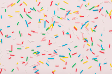 flat lay of colorful sprinkles over pink background, festive decoration for banner, poster, flyer, card, postcard, cover, brochure, designers