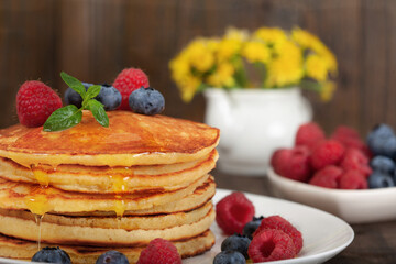American pancakes with fresh blueberry, raspberry and honey. Healthy morning breakfast. Wooden background.