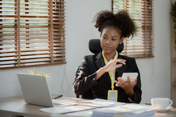 Young African American businesswoman working on laptop with documents and stressed over worked from...