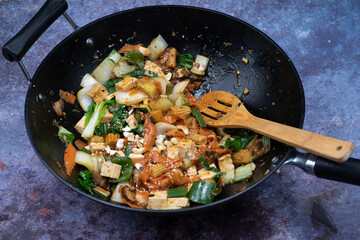 Vegan noodles, tofu and vegetable mix stir fry in wok,