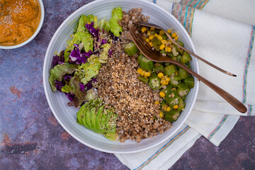 Protein bowl consisting of buckwheat, hemp seeds, okra and corn stir fry, salad and avocado