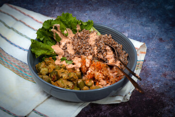 Vegan bowl consisting of buckwheat, souerkraut, okra, vegan sauce and greens