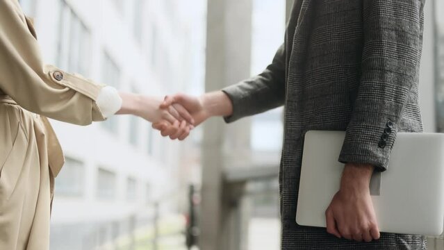 Businesswoman shaking hands with a businessman near modern office centre Businesspeople closing a deal and concluding a contract with a handshake outdoors Deal Partners concept